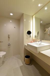 a bathroom with a toilet, sink, and mirror at HARRIS Hotel & Conventions Ciumbuleuit - Bandung in Bandung