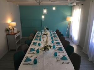 une longue table dans une pièce aux murs bleus dans l'établissement Hôtel Restaurant de la Place, à Saint-Jean-dʼAngély