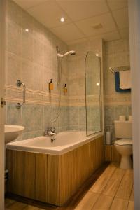 a bathroom with a bath tub and a toilet at Oliver Cromwell Hotel in March