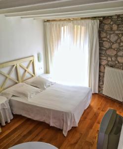 um quarto com uma cama e uma grande janela em El Castell de la Pobla de Lillet (Adults Only) em La Pobla de Lillet