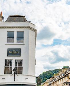 um edifício branco com uma placa de caixa preta em The Black Fox em Bath