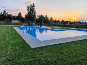 einen Pool auf einem Feld mit Sonnenuntergang im Hintergrund in der Unterkunft Complex Pastravaria Albota in Arpaşu de Sus