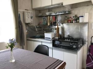a small kitchen with a table and a stove at Yuigahama Apart in Kamakura