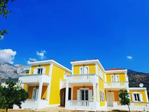 a yellow and white house with mountains in the background at Villa Aggeliki in Marathokampos