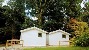 two white buildings in a yard with trees at Dunmore Gardens Log Cabins in Carrigans