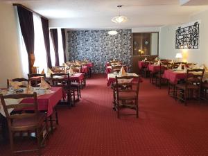 ein Esszimmer mit Tischen und Stühlen mit rotem Tischtuch in der Unterkunft Kirchberg Hotel garni in Saarbrücken