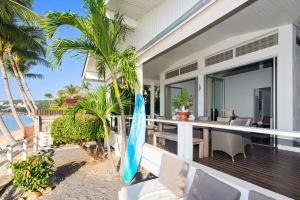 an outdoor patio with a table and chairs and palm trees at Ban Mok Talay Beachfront Villa in Bang Rak Beach