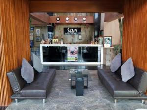 a living room with two leather couches and a table at Izen Budget Hotel & Residence in Rayong