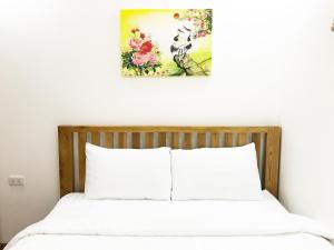 een bed met witte lakens en een foto aan de muur bij My Khe Beach Apartment Sea View in Da Nang