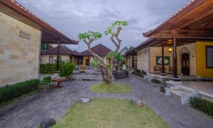 a courtyard with a tree in the middle of a building at Taman Sari Cottages in Kuta