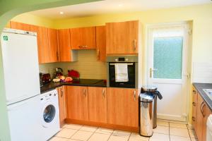 a kitchen with wooden cabinets and a washer and dryer at Little Lulworth in Bordon