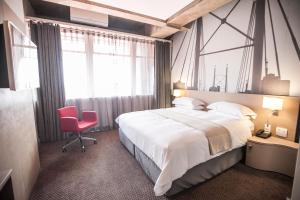 um quarto com uma cama grande e uma cadeira vermelha em Reef Hotel em Joanesburgo