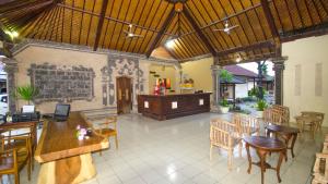 un restaurante con mesas y sillas de madera y una barra en Taman Sari Cottages, en Kuta