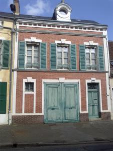 an old brick building with green doors and green shutters at Le 39 Bis in Rémalard