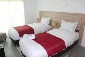 2 camas en una habitación de hotel con sábanas blancas y rojas en Dakhla Sur Mer Hôtel, en Dakhla