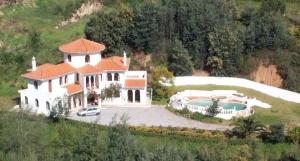 uma grande casa branca com uma piscina numa colina em Quinta Da Mimosa em Monchique