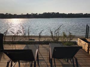 two chairs and tables sitting on a dock near a body of water at Appartement Du Lac in Hossegor