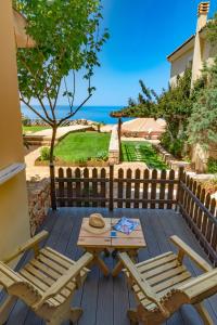 a wooden deck with two chairs and a table at Petani Bay Hotel - Adults Only in Vóvikes