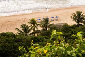 a beach with palm trees and blue umbrellas at Hotel Ponta do Madeiro in Pipa