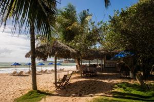 a beach with chairs and umbrellas and the ocean at Hotel Ponta do Madeiro in Pipa