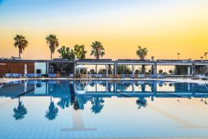 ein Pool mit Palmen und ein Gebäude in der Unterkunft Miramar Hotel Resort and Spa in Tripoli
