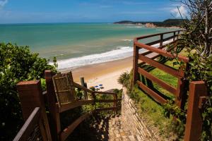 a wooden stairway leading to a beach with the ocean at Hotel Ponta do Madeiro in Pipa