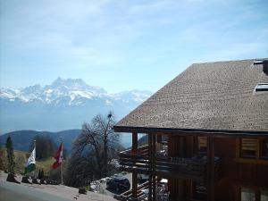 a ski lodge with mountains in the background with flags at Résidence Castel Club Leysin Parc in Leysin