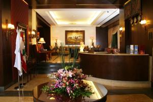 a lobby with a reception desk and flowers on a table at Markazia Suites in Beirut