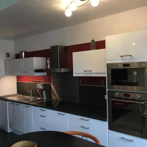 ランスにあるBedinReims "red bottle" 105m2 on one level, 4 bedrooms with double beds wifi free ideal 4 à 8 Adultes 2 bathrooms free parkingのキッチン(白いキャビネット、黒の電化製品付)