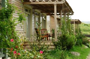 un porche de una casa con mesa y sillas en Delta Resort Treetop by Eight Continents, en Tulcea