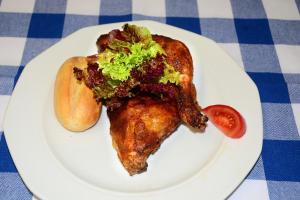 un plato blanco con un sándwich de pollo y un tomate en Hotel Das Schlössl, en Bad Tölz