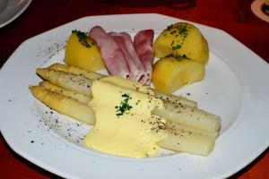 a plate of food with ham and cheese and lemons at Hotel Das Schlössl in Bad Tölz