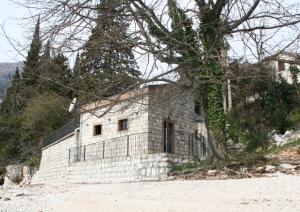 un edificio de piedra con un árbol delante de él en House on the beach en Kotor
