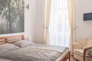 a bedroom with a bed and a chair and a window at Spacious old town luxury apartment in Linz