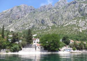 a village on the water with mountains in the background at House on the beach in Kotor