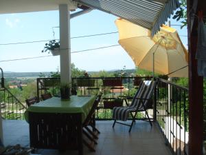 - un balcon avec une table, des chaises et un parasol dans l'établissement Appartement Nicole BENKOVAC, à Benkovac
