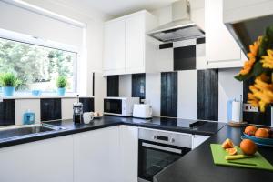 a kitchen with white cabinets and black counter tops at Netherton House in Wishaw
