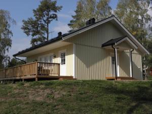 uma pequena casa amarela com um deque numa colina em Söderö stugby em Finström