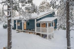 ein blaues Haus mit schneebedecktem Dach im Schnee in der Unterkunft Auroracabin Chalets in Saariselkä