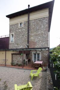 a stone house with a patio and green chairs at Appartamento Ai Due Pioppi in Lucca
