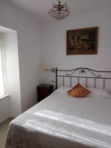 a bedroom with a white bed with a chandelier at Casa Rural Mimbrero in Aldeadávila de la Ribera