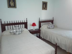 a bedroom with two beds and a table with a lamp at Casa Rural Mimbrero in Aldeadávila de la Ribera