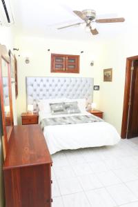 a bedroom with a white bed and a wooden table at Hotel Aluge in Santo Domingo