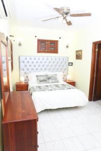 Schlafzimmer mit einem weißen Bett und einem Holztisch in der Unterkunft Hotel Aluge in Santo Domingo
