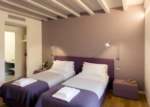 two beds in a room with purple and white at Manzoni 124 Bed&Relax in Esine