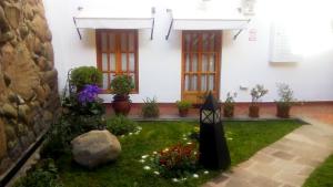 einen Garten vor einem weißen Haus mit Blumen in der Unterkunft Quinua Boutique Apartments in Cusco