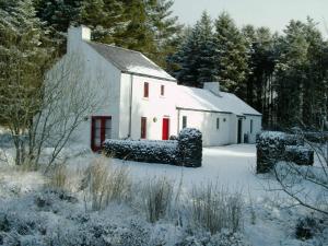 a white house with red doors in the snow at An Creagán Self Catering Cottages in Greencastle