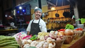 Um homem está atrás de um balcão com vegetais. em PP Red Tuna Hut em Phi Phi Don