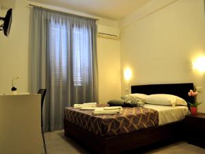 a bedroom with a bed with a large window at Hotel Sikania in San Vito lo Capo