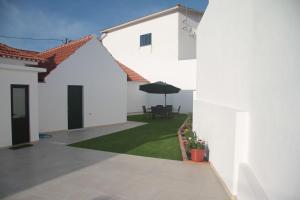 a white house with a patio with an umbrella at Vivenda Maria da Nazaré in Picamilho